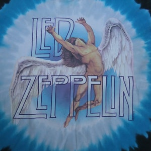 May include: Tie-dye t-shirt featuring the Led Zeppelin band logo and a graphic of a winged figure. The shirt has a blue and white spiral design. The band's name is in a blue outline font.