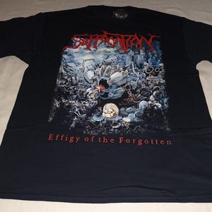 May include: Black t-shirt with the band name "Suffocation" in red, above a detailed graphic of a battle scene. The text "Effigy of the Forgotten" is printed in red below the graphic. The shirt is made of a soft material.
