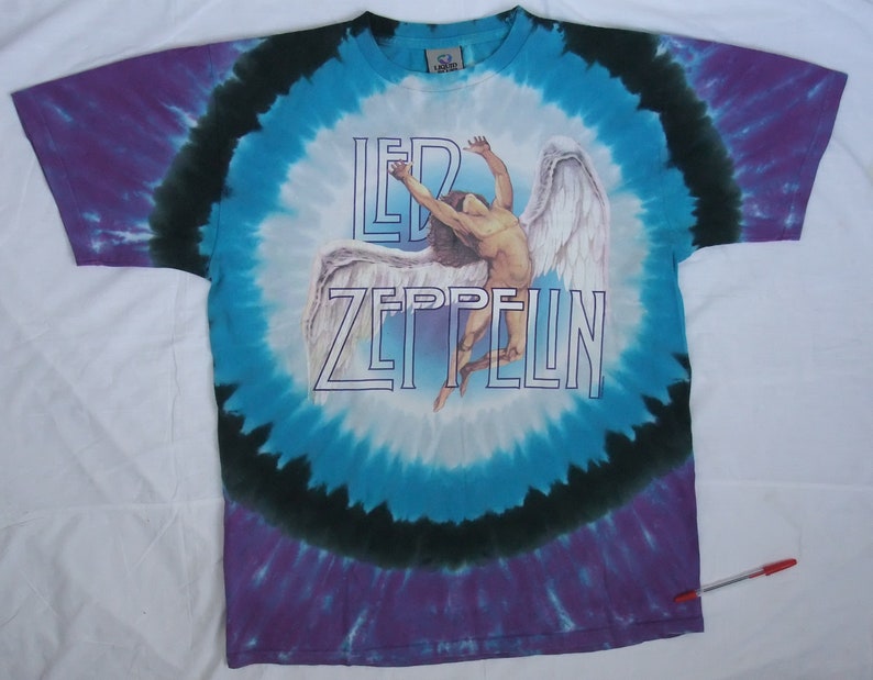May include: Tie-dye t-shirt with a circular pattern in shades of blue, purple, and black. The shirt features the band name "LED ZEPPELIN" in white block letters, along with an image of a winged figure.