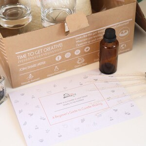 May include: A brown cardboard box with the text "TIME TO GET CREATIVE!" and "JOIN | SHARE | REFER". The box contains a candle making kit with glass jars, wicks, and a bottle of essential oil.