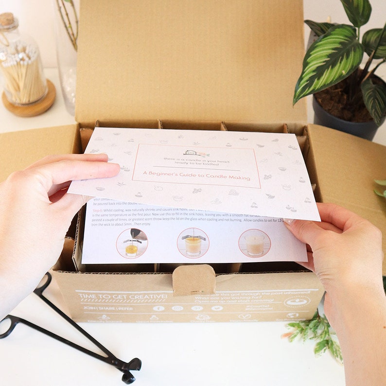 May include: A brown cardboard box with a white instruction sheet that says "A Beginner's Guide to Candle Making". The box is open and the instruction sheet is being pulled out. The box contains multiple glass candle jars and a pair of black metal candle wick trimmers. The text "Time to Get Creative!" is printed on the box.