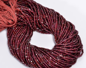 May include: A strand of deep red gemstone beads, likely garnet, with a square shape and a faceted finish. The beads are strung on a cord and have a tassel at one end.
