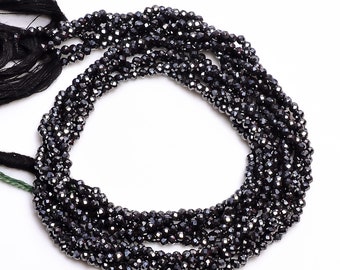 May include: A strand of black faceted gemstone beads. The beads are small and have a shiny, metallic finish.