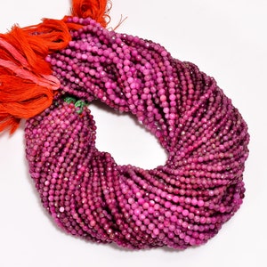 Puede incluir: Una hebra de cuentas de rubí rosa, de aproximadamente 4 mm de tamaño, con un acabado facetado. Las cuentas están enhebradas en un hilo rojo y están listas para la elaboración de joyas.