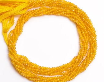 May include: A strand of bright yellow faceted gemstone beads. The beads are small and round, and they are strung on a thin thread. The beads are arranged in a circular pattern, and they are all the same size and shape.
