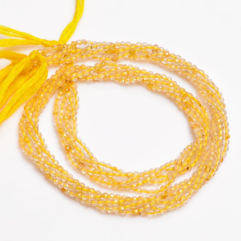 K&ouml;nnte beinhalten: Eine Str&auml;hne gelber Citrin-Edelsteinkugeln. Die Kugeln sind facettiert und haben ein durchscheinendes Aussehen. Die Str&auml;hne ist etwa 45 cm lang und auf einer durchsichtigen Gummikordel aufgef&auml;delt.