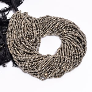 Peut inclure: Un brin de petites perles de pyrite facettées de couleur brun doré. Les perles sont disposées en cercle, créant un affichage décoratif et accrocheur.