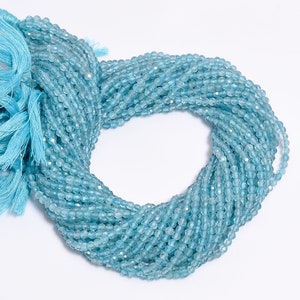 May include: A strand of light blue aquamarine beads, approximately 4mm in size, with a faceted finish. The beads are strung on a clear thread and are arranged in a circular shape.