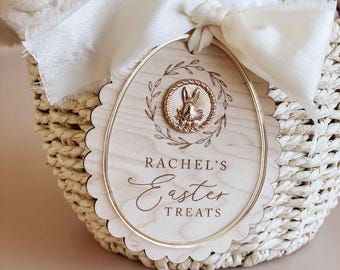 May include: A wooden Easter egg-shaped tag with a gold bunny design and the text "Rachel's Easter Treats".