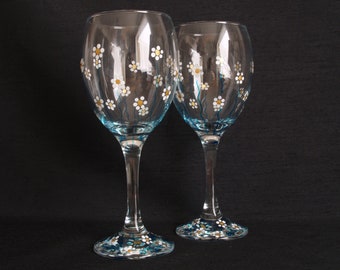 Pair of hand painted wine glasses decorated with daisies in a summery gold, white and blue design. Would make a lovely gift.