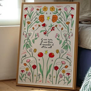 以下が含まれることがあります： オレンジ、赤、黄色、ピンクの花柄が特徴の額入りアートプリント。アートワークには、手書き風の「it was rare, I was there, I remember it all too well」というテキストが含まれています。フレームは木製です。
