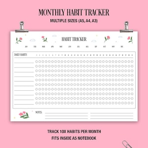 Könnte beinhalten: Ein weißer Gewohnheitstracker mit dem Text "Monthly Habit Tracker" und "Habit Tracker". Der Tracker enthält Bereiche für tägliche Gewohnheiten und Notizen, mit Monaten oben. Das Design zeigt florale Akzente und wird von silbernen Clips gehalten.
