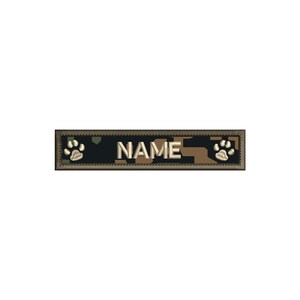 May include: A camouflage-patterned dog ID tag with a white border and the word "NAME" in white text. The tag has a paw print on each end.