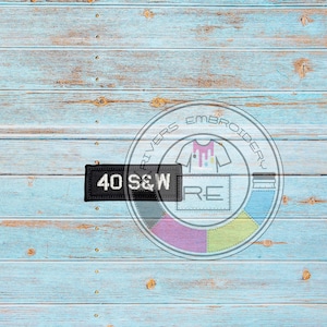 May include: A black patch with white text that reads "40 S&W" on a blue wood background. The patch is in front of a circle with the text "Rivers Embroidery" and a colorful design.