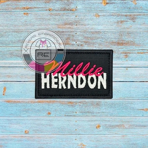 May include: Black embroidered patch with white text that reads "Millie Herndon" in a pink cursive font.