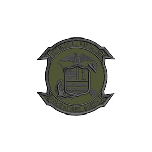 May include: An olive green embroidered patch featuring the 1st Medical Battalion emblem. The design includes an eagle, a shield with the number 1, an anchor, and a medical cross. The text 1ST MEDICAL BATTALION and FRAUDATORES MORTIS is stitched.