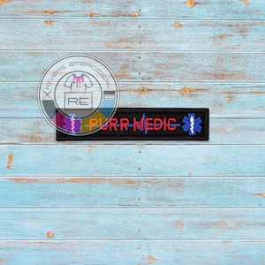 May include: Black embroidered patch with the text "PURR-MEDIC" in red and a blue star of life symbol.