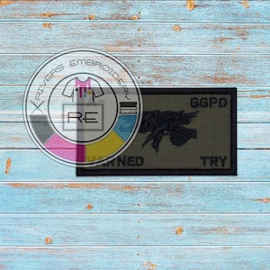May include: A green and black embroidered patch with a stylized bird design and the text "GGPD" and "TRY".