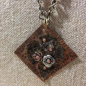 Unique artisan necklace with a riveted pendant in mixed metals of copper, brass, and bronze. Handmade chain, mixed metal