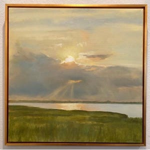 May include: A square oil painting in a thin gold frame depicting a landscape at sunset. The scene features a green grassy marsh in the foreground, a calm body of water in the middle ground, and a cloudy sky with sunbeams radiating downward.