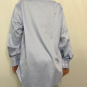 May include: A light blue long-sleeved button-down shirt with a classic collar and long sleeves. The shirt is made of a smooth, lightweight fabric.