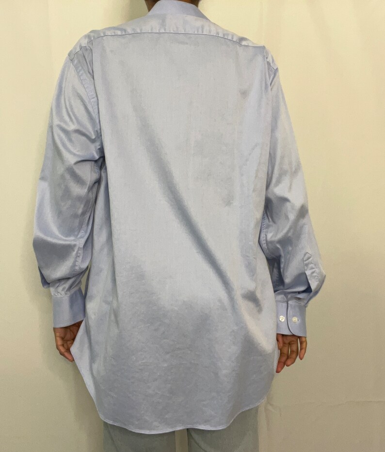 May include: A light blue long-sleeved button-down shirt with a classic collar and long sleeves. The shirt is made of a smooth, lightweight fabric.