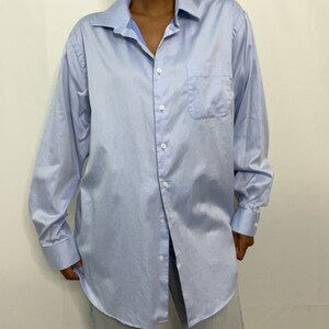 May include: A light blue long-sleeved button-down shirt with a single chest pocket.