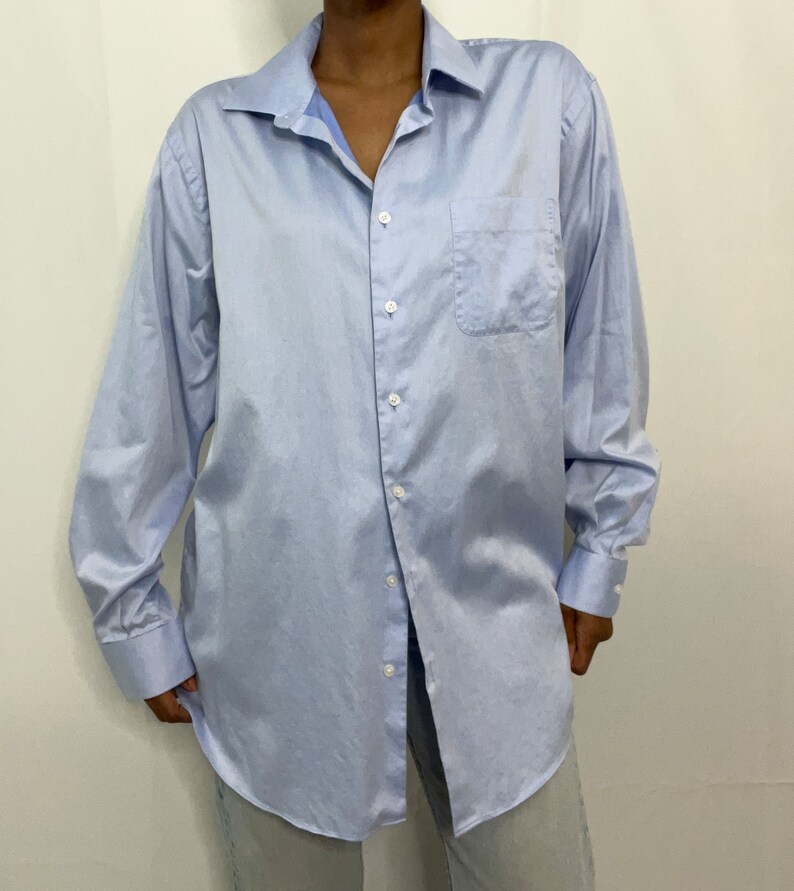 May include: A light blue long-sleeved button-down shirt with a single chest pocket.