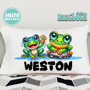 May include: White pillowcase with a green and blue cartoon frog design. The pillowcase has the name "WESTON" printed in black letters.