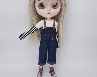 May include: A doll with blonde hair wearing a white shirt with black stripes, blue denim overalls, and red and brown sneakers.
