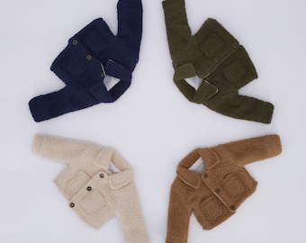 May include: Four faux fur jackets in different colors: navy blue, beige, brown, and olive green. Each jacket has a button closure and a pocket on the front.
