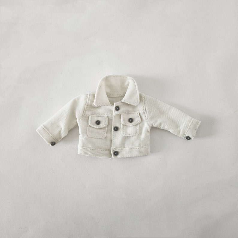 May include: A white corduroy jacket with a button closure and two flap pockets.