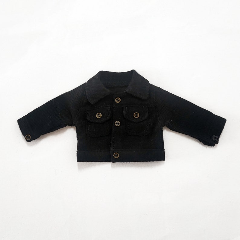 May include: A black corduroy jacket with a collared neckline, two flap pockets, and button closures.