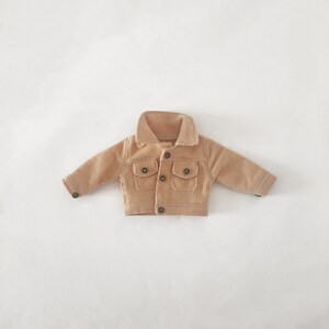May include: A tan corduroy jacket with a button closure and two front pockets.