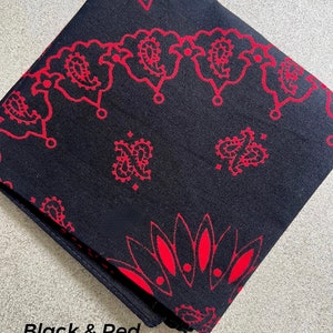 May include: Black and red bandana with a paisley pattern. The bandana is folded and features a repeating design of red paisley shapes on a black background. The text "Black & Red" is visible.