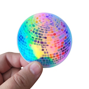 Könnte beinhalten: Ein regenbogenfarbener, irisierender Discokugel-Aufkleber. Der Aufkleber ist rund und hat eine spiegelnde Oberfläche mit kleinen Quadraten.