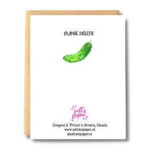 May include: A blank greeting card featuring a watercolour illustration of a green pickle on the front. The card reads "BLANK INSIDE" and has the text "salt & paper" in pink at the bottom. The card is designed and printed in Ontario, Canada.