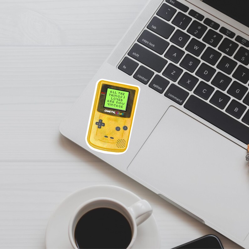 May include: A yellow Game Boy Color with a green screen displaying the text "ALL THE THINGS I LOVED ARE NOW VINTAGE".