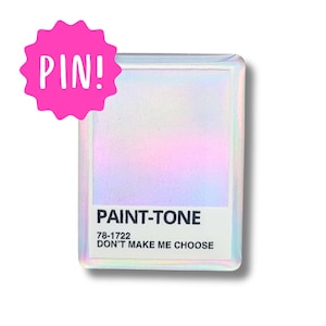 May include: A holographic iridescent white pin with the text "PAINT-TONE 78-1722 DON'T MAKE ME CHOOSE" in black.