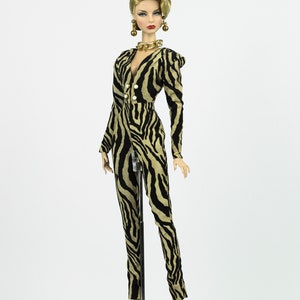 May include: A fashion doll wearing a black and tan zebra print jumpsuit with gold jewellery and black heels.