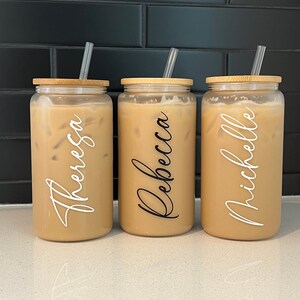 May include: Three clear glass tumblers with bamboo lids and straws. Each tumbler has a name written on it: Theresa, Rebecca, and Michelle.