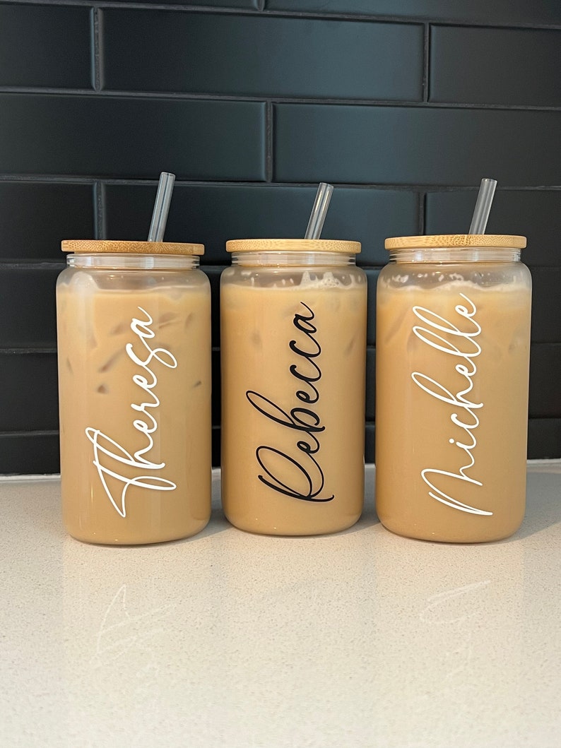 May include: Three clear glass tumblers with bamboo lids and straws. Each tumbler has a name written on it: Theresa, Rebecca, and Michelle.