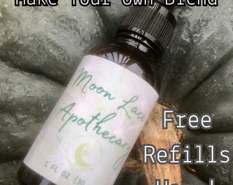 May include: A dark amber glass dropper bottle with a black cap and a white label featuring the text Moon Lace Apothecary, 1 FL OZ (30 mL), and a crescent moon logo. The text Make Your Own Blend and Free Refills Here is visible.