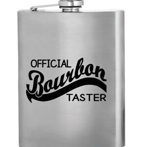 May include: A silver flask with the text "OFFICIAL Bourbon TASTER" printed on it.