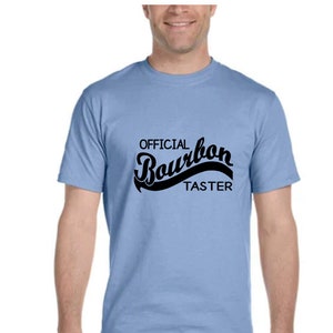 May include: A light blue t-shirt with the text "OFFICIAL Bourbon TASTER" in black.