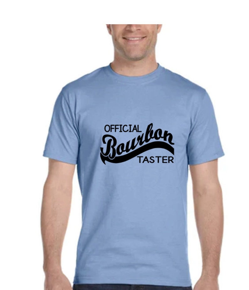 May include: A light blue t-shirt with the text "OFFICIAL Bourbon TASTER" in black.