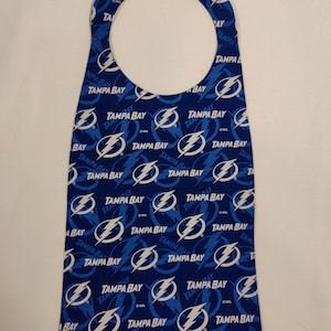 May include: A blue fabric bib with a white lightning bolt and the words "Tampa Bay" repeated throughout the design.