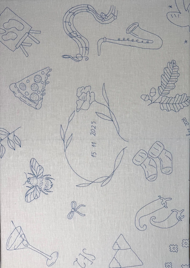 May include: A light gray fabric featuring dark blue line art embroidery of various icons including a saxophone, a pizza slice, a bee, baby socks, chili peppers, a martini glass, and a central floral wreath enclosing the date 15 11 2025.