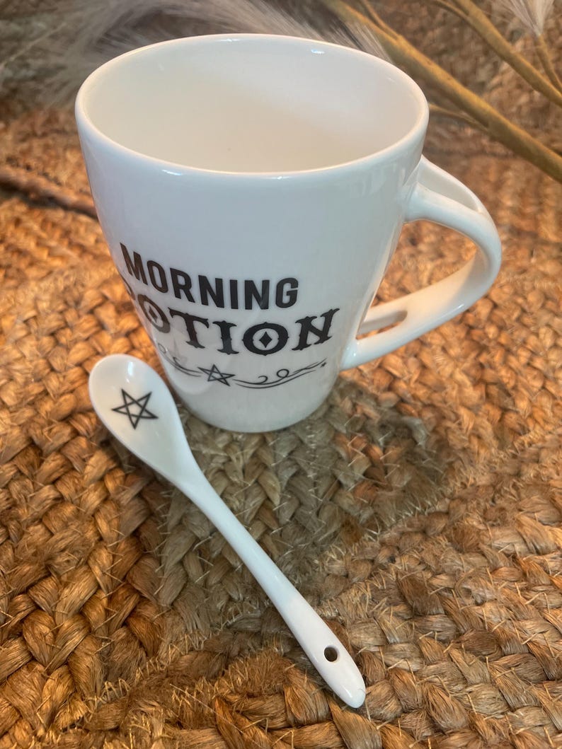 May include: White ceramic mug with black text that reads "Morning Potion" and a small white ceramic spoon with a black pentagram design.