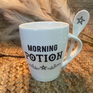 May include: White ceramic mug with a black design that says "Morning Potion" and a star. The mug has a white ceramic spoon with a black star design.